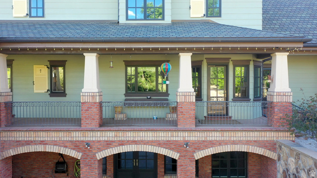 426 West Center Street Parowan, UT 84761 - Photo 82 of 107 Multi-level exterior featuring a covered porch with stone columns and wrought iron railing, brick archways, multiple windows with dark trim, and light green siding
