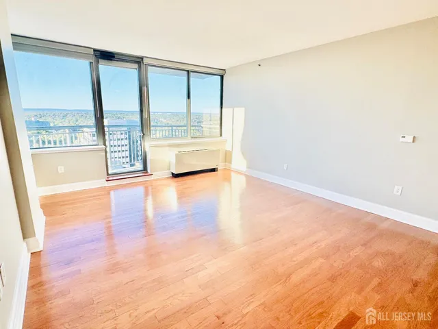 a view of an empty room with wooden floor and a shower