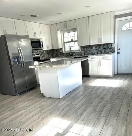 a kitchen with granite countertop a refrigerator oven a sink a window and wooden floor