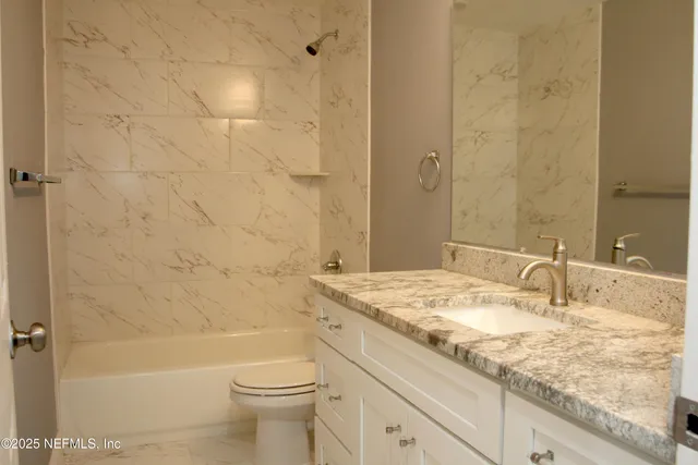 a bathroom with a granite countertop sink a toilet and shower