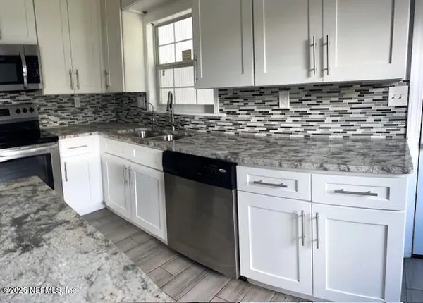 a kitchen with granite countertop white cabinets and white appliances
