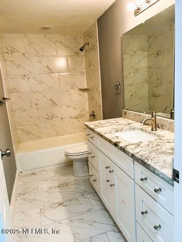 a bathroom with a granite countertop sink toilet and shower
