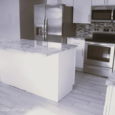 a kitchen with granite countertop a stove and a microwave