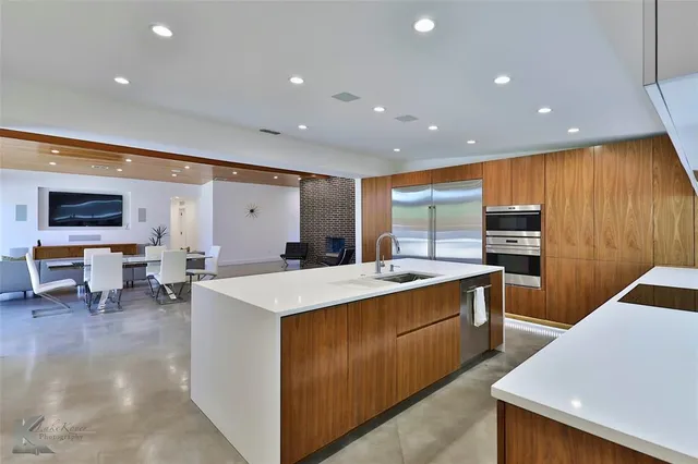 a large kitchen with stainless steel appliances a large counter top space and wooden floors