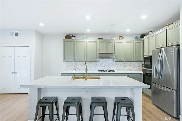 a kitchen with kitchen island stainless steel appliances a sink stove and refrigerator