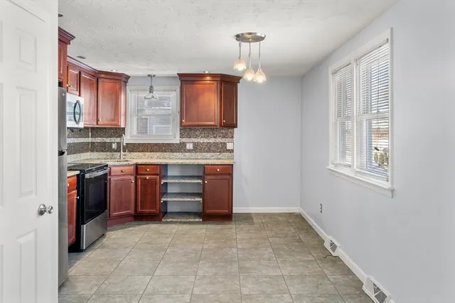 a large kitchen with stainless steel appliances granite countertop a stove a sink and a refrigerator