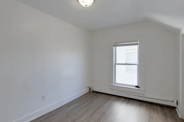 an empty room with wooden floor and window