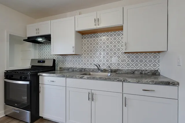 a kitchen with granite countertop white cabinets and a stove