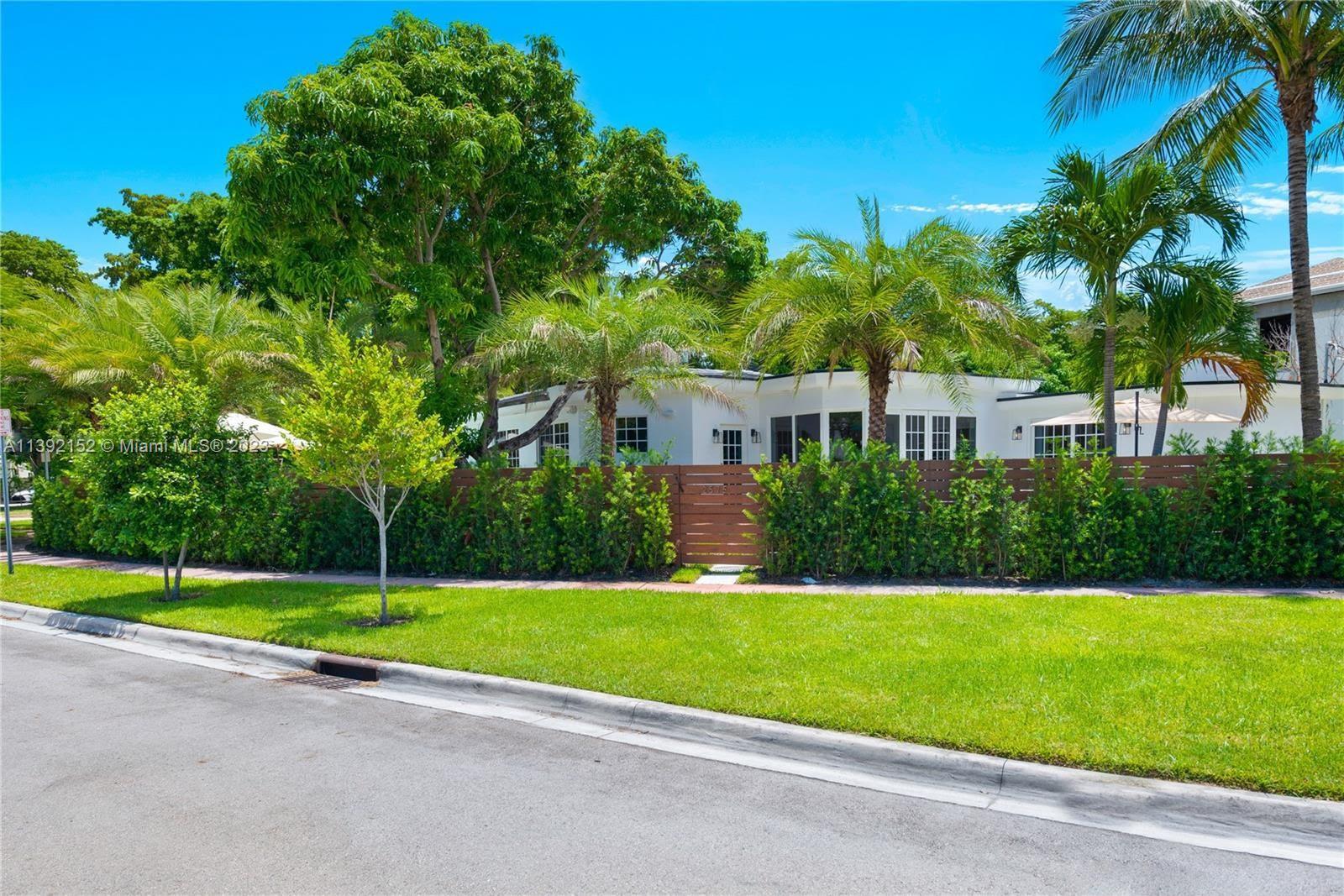 a view of a house with a yard and palm trees