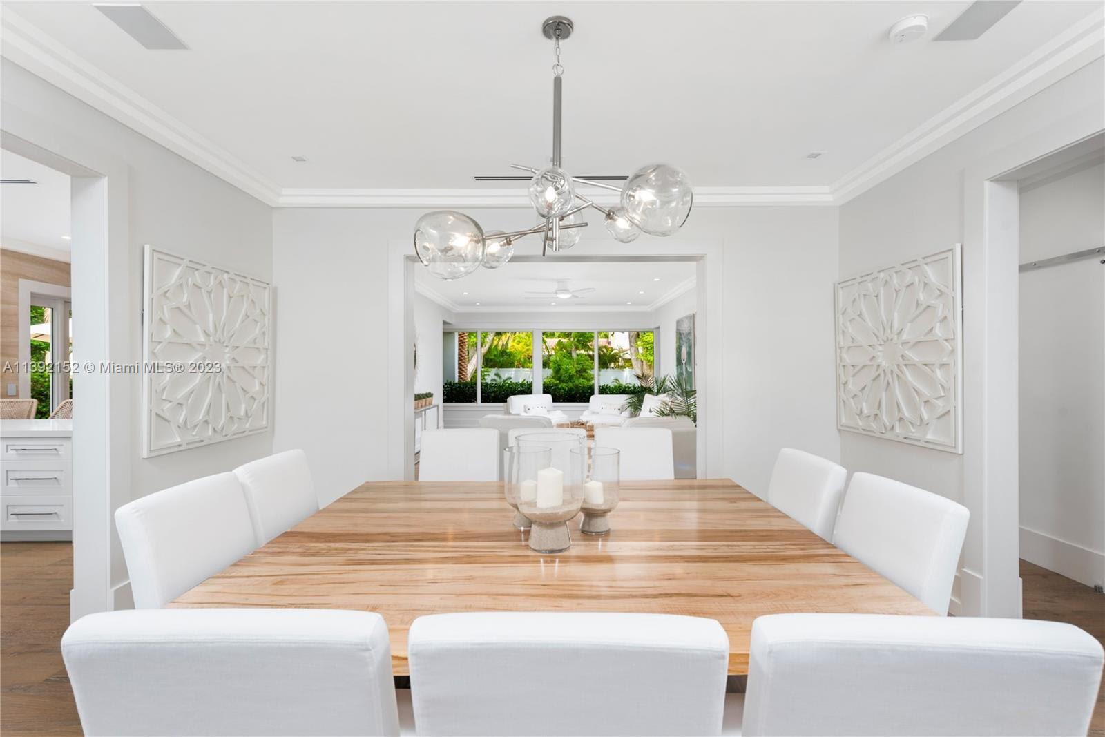2575 Pine Tree Drive Miami Beach, FL 33140 - Photo 4 of 37 a view of a dining room with furniture a chandelier and wooden floor