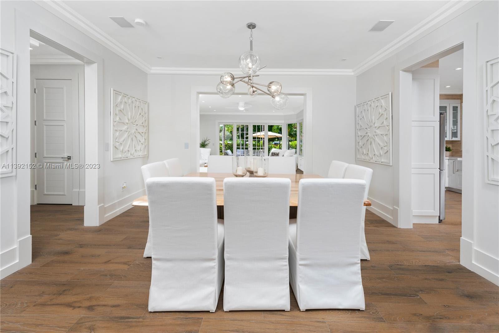 2575 Pine Tree Drive Miami Beach, FL 33140 - Photo 5 of 37 a view of a dining room with furniture a chandelier and wooden floor