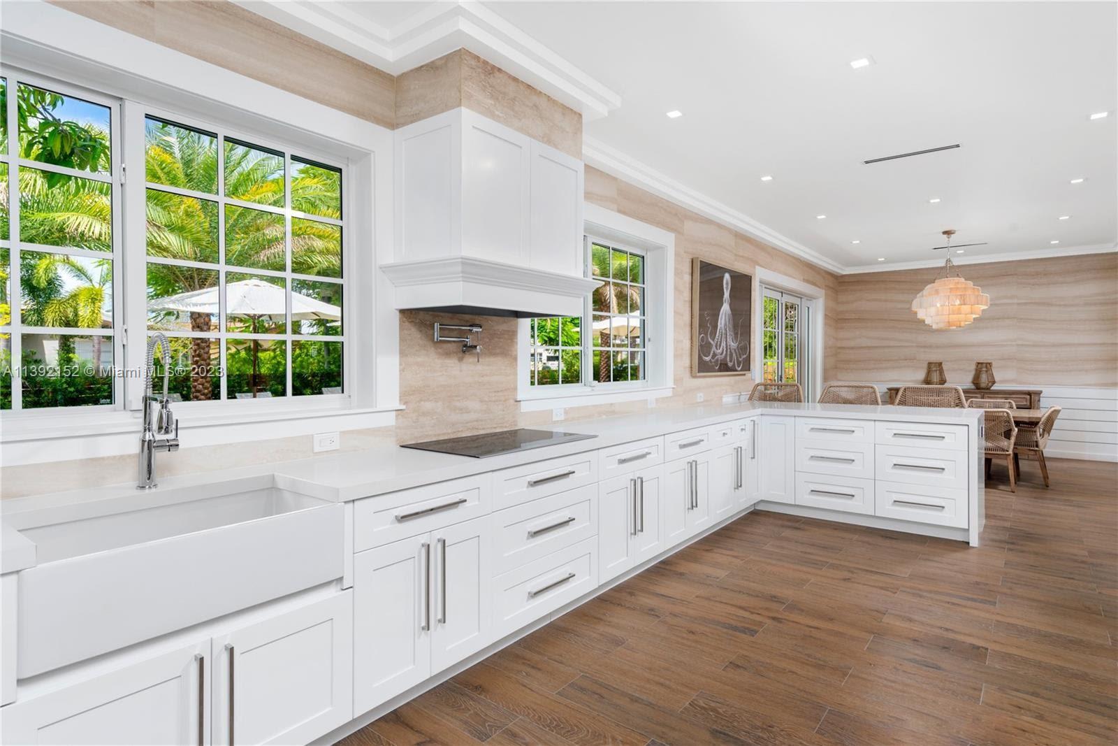 2575 Pine Tree Drive Miami Beach, FL 33140 - Photo 7 of 37 a kitchen with kitchen island granite countertop a stove and white cabinets