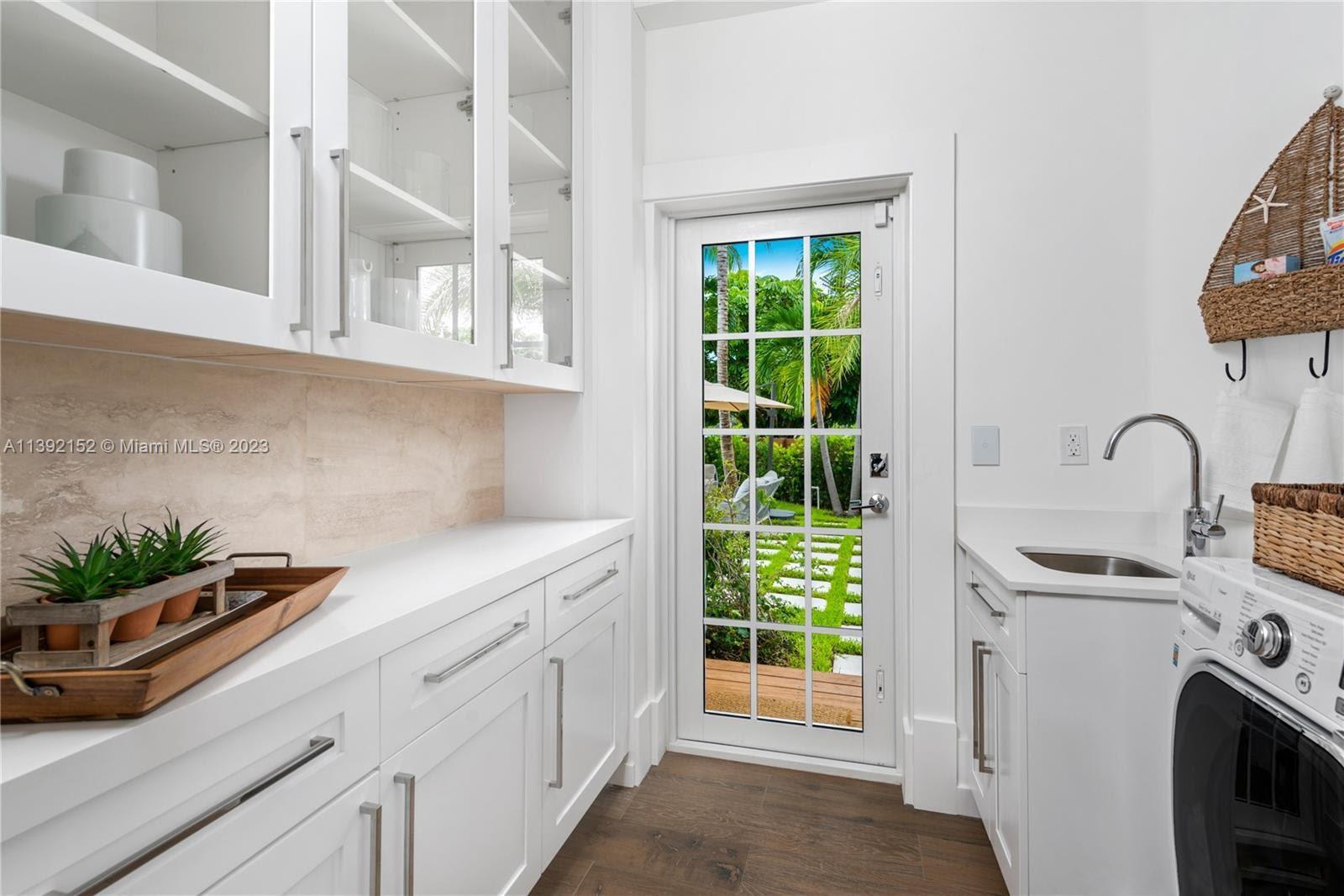 2575 Pine Tree Drive Miami Beach, FL 33140 - Photo 8 of 37 a kitchen with stainless steel appliances a sink a stove and white cabinets next to a window