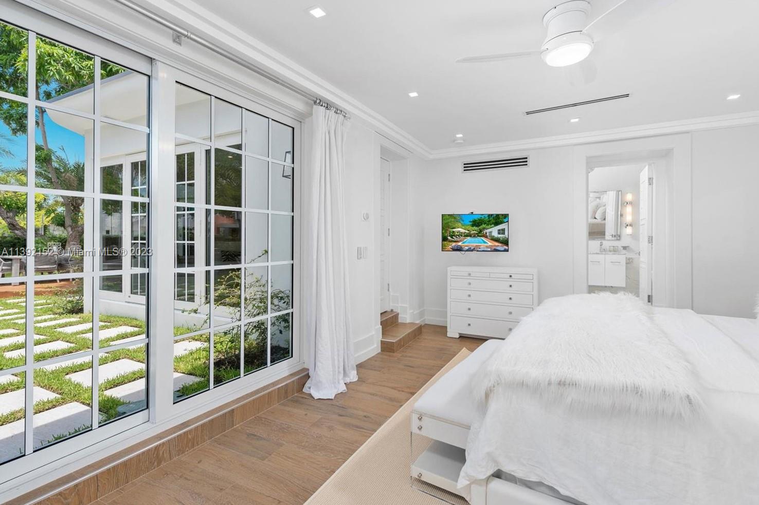 2575 Pine Tree Drive Miami Beach, FL 33140 - Photo 10 of 37 a bedroom with a bed and glass door