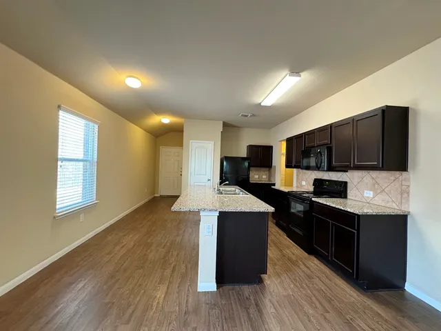 a large kitchen with stainless steel appliances wooden floors and wooden cabinets