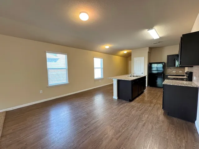 an open kitchen with wooden floor and black appliances