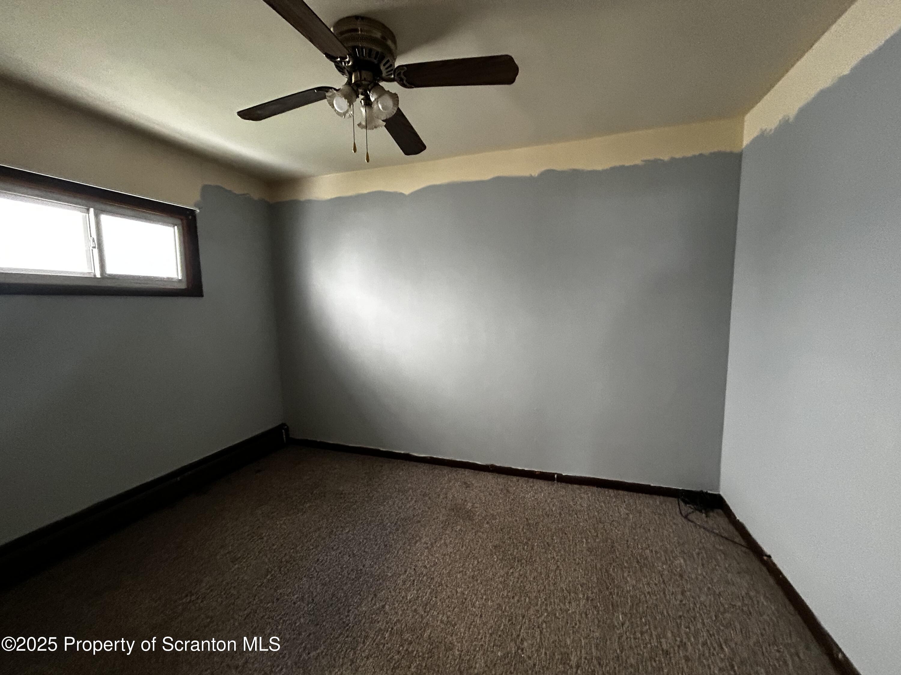 716 Main Street Carbondale, PA 18407 - Photo 6 of 9 an empty room with a ceiling fan and window
