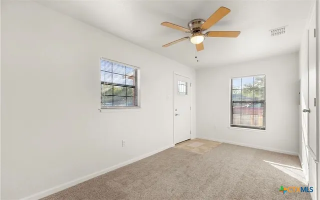 an empty room with ceiling fan and window