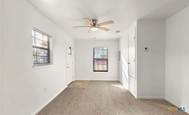 a view of a big room with windows and chandelier fan
