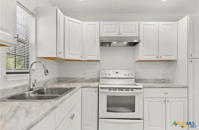 a kitchen with granite countertop white cabinets and white appliances