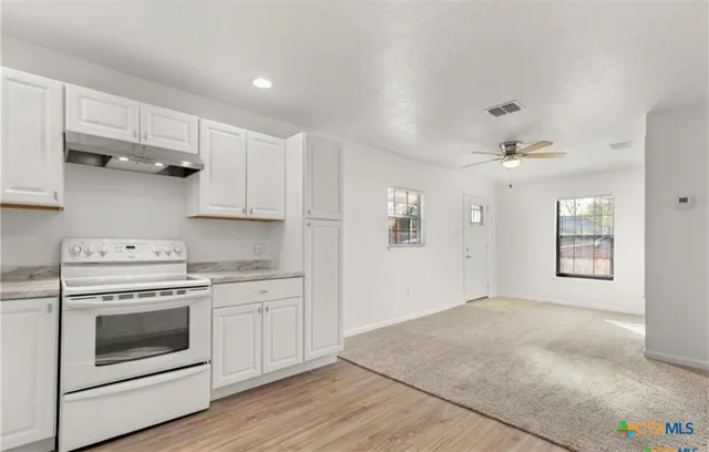 a kitchen with stainless steel appliances white cabinets and wooden floors