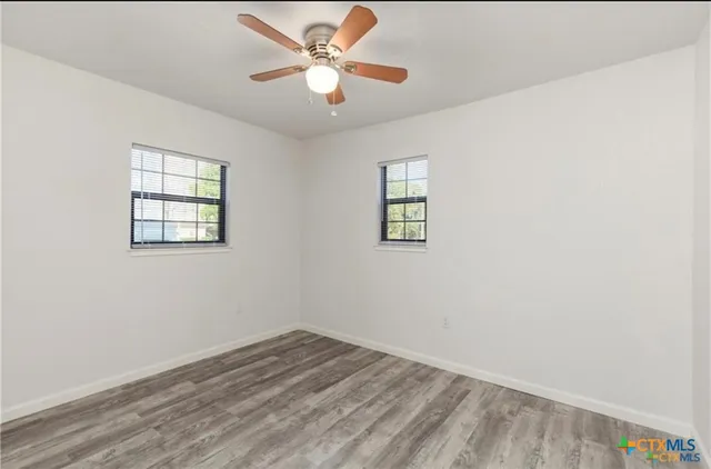 an empty room with a window and a fan