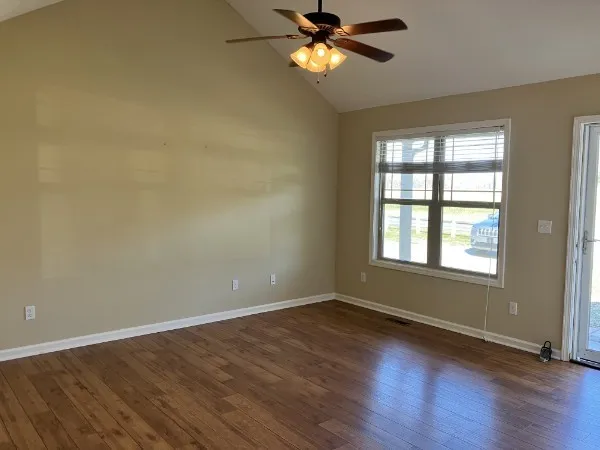 a view of an empty room with wooden floor and a window