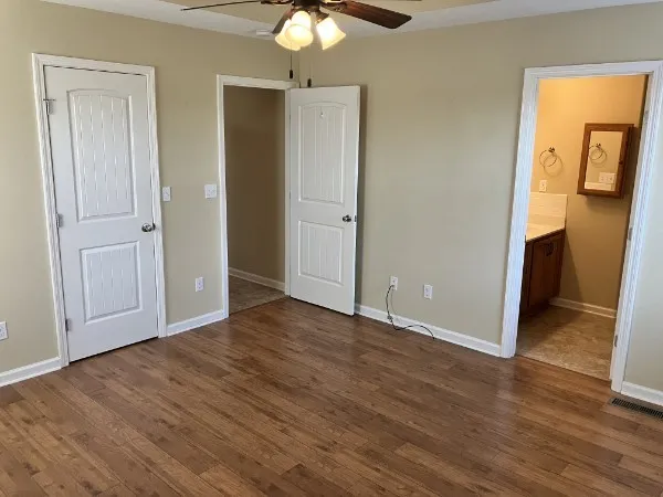 an empty room with wooden floor and a ceiling fan