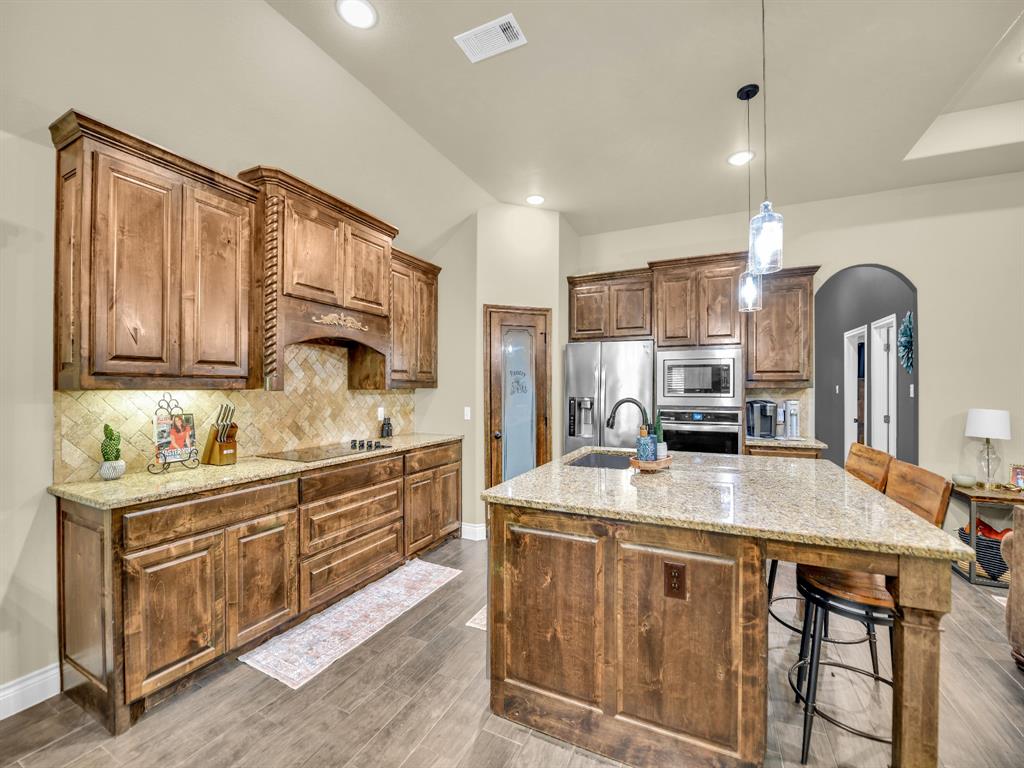 156 Cottongame Road Weatherford, TX 76088 - Photo 10 of 35 a kitchen with kitchen island granite countertop a stove top oven a sink dishwasher and cabinets with wooden floor