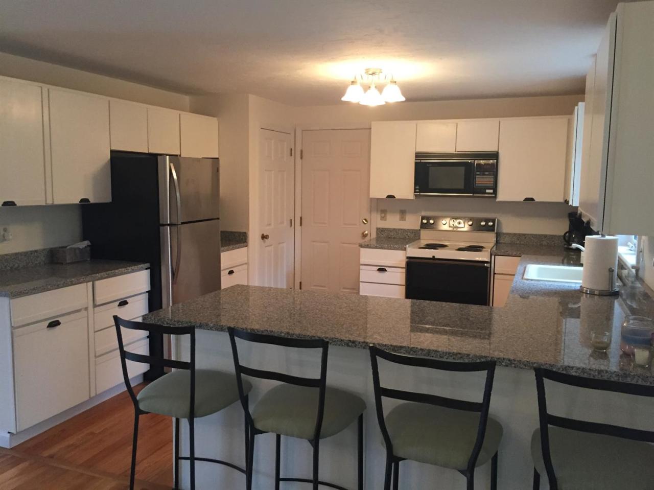 17 Wintergreen Road Mashpee, MA 02649 - Photo 8 of 34 a kitchen with kitchen island granite countertop a table chairs microwave and refrigerator