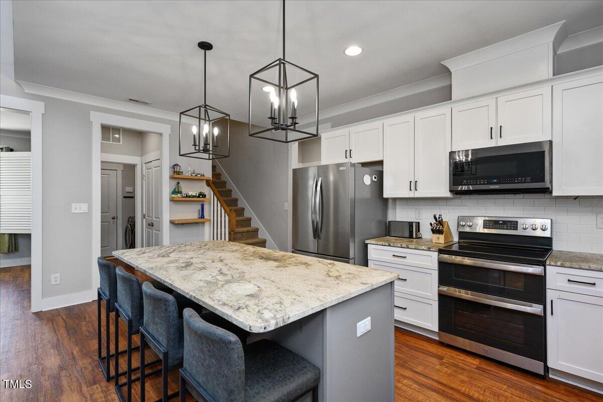 1415 Pine Ridge Road Spring Hope, NC 27882 - Photo 8 of 25 a kitchen with stainless steel appliances kitchen island a wooden floor and white cabinets