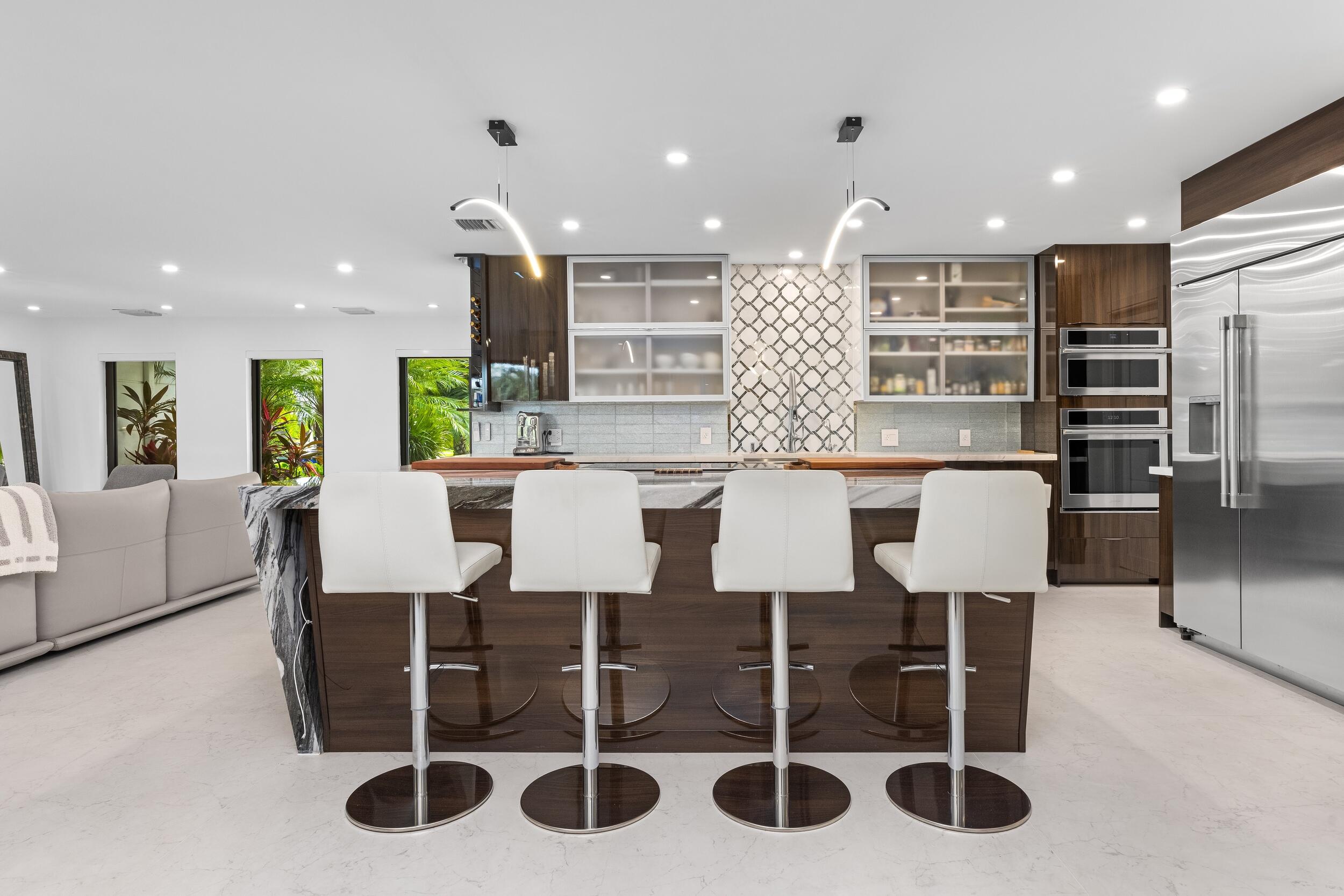 843 Northeast Mulberry Drive Boca Raton, FL 33487 - Photo 14 of 57 a kitchen with stainless steel appliances kitchen island granite countertop a table and chairs in it
