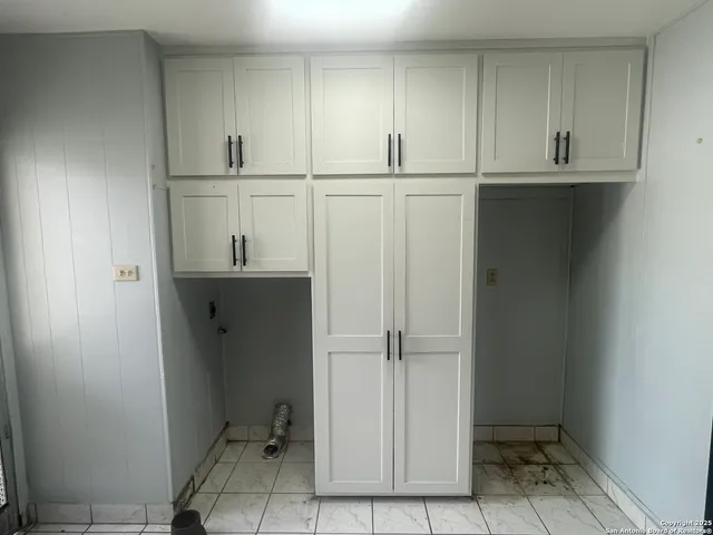 a view of cabinets and utility room with closet