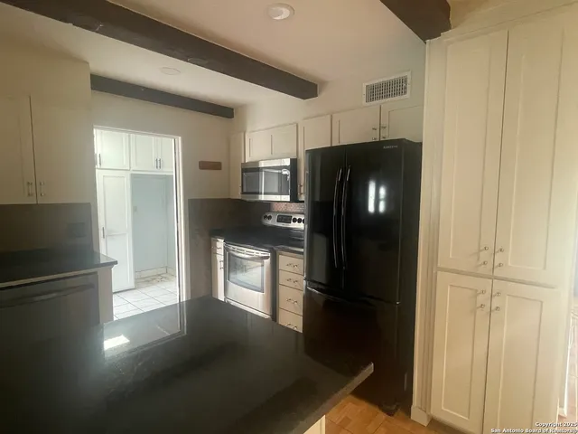 a kitchen with a refrigerator and white cabinets