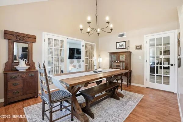 a view of a dining room with furniture a chandelier and wooden floor