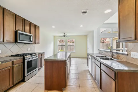 a kitchen with stainless steel appliances granite countertop a stove top oven a sink dishwasher a refrigerator and a microwave