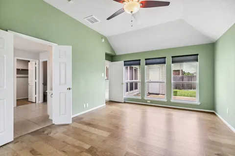 an empty room with ceiling fan and windows