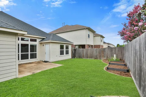 a view of a backyard with wooden fence and a large tree