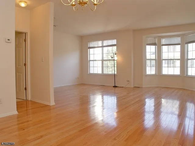 an empty room with wooden floor and windows with curtains view