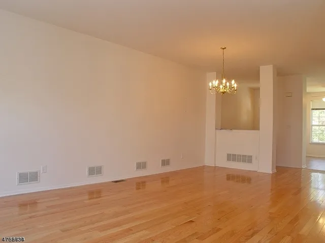 an empty room with wooden floor and chandelier