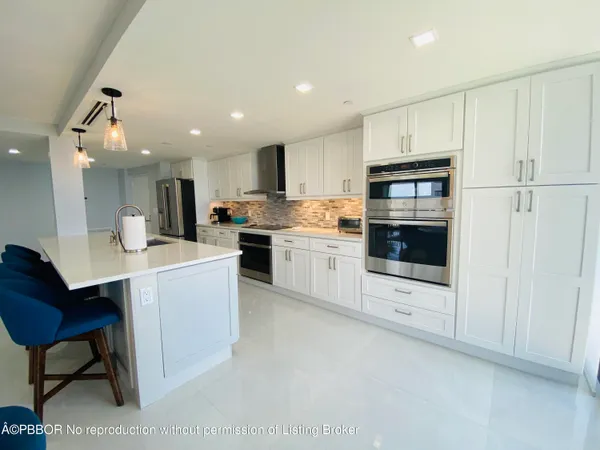 a kitchen with stainless steel appliances kitchen island granite countertop a stove top oven a sink dishwasher and white cabinets with wooden floor