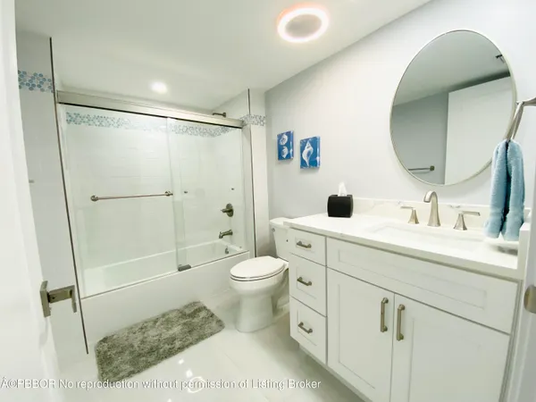 a bathroom with a toilet sink vanity granite and shower