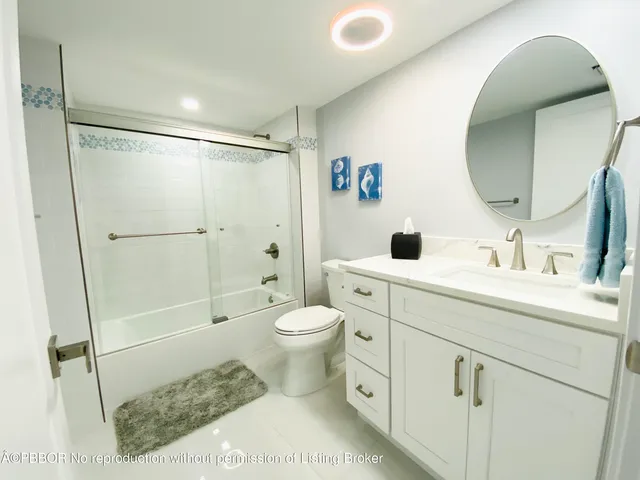 a bathroom with a toilet sink vanity granite and shower