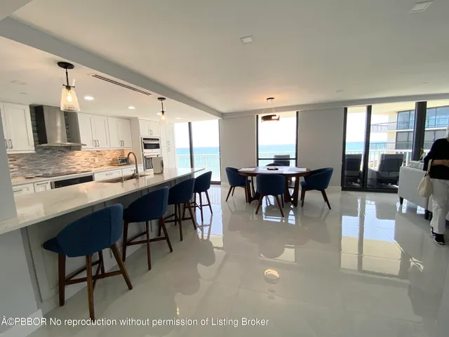 a dining hall with stainless steel appliances kitchen island granite countertop furniture and a large window