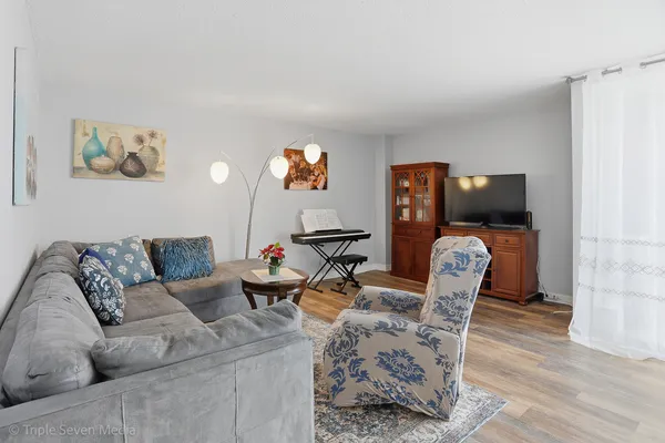 a living room with furniture a flat screen tv and wooden floor