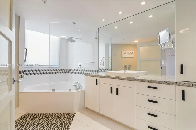 a bathroom with a granite countertop sink a large mirror and a bathtub