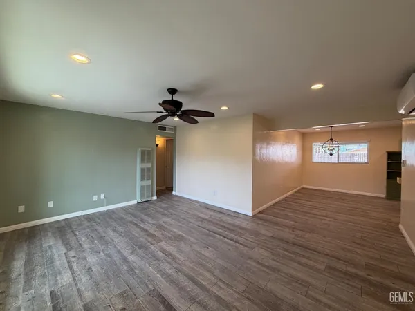 a view of a room with wooden floor a ceiling fan and windows