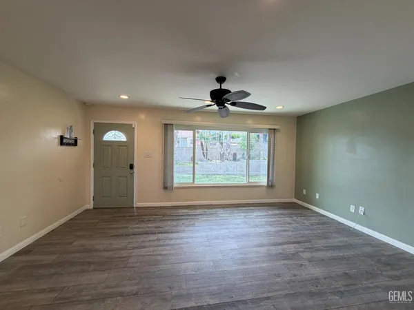 a view of an empty room with a window and wooden floor