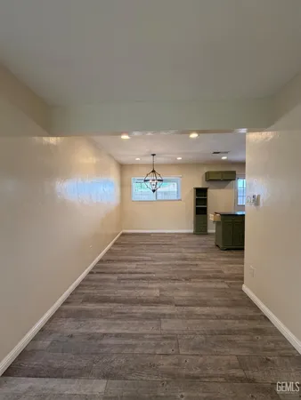 a view of a hallway with wooden floor and a kitchen