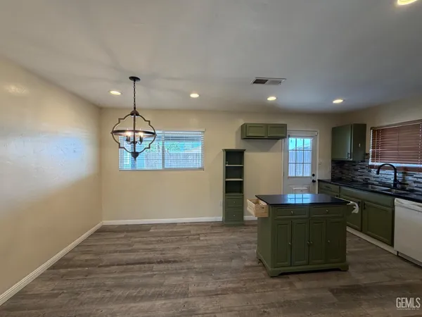 a kitchen with kitchen island stainless steel appliances a table chairs refrigerator and sink